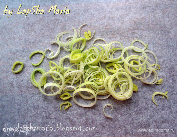 Кольцами нарежьте лук-порей и выложите его на подготовленный пласт бумаги для выпечки.