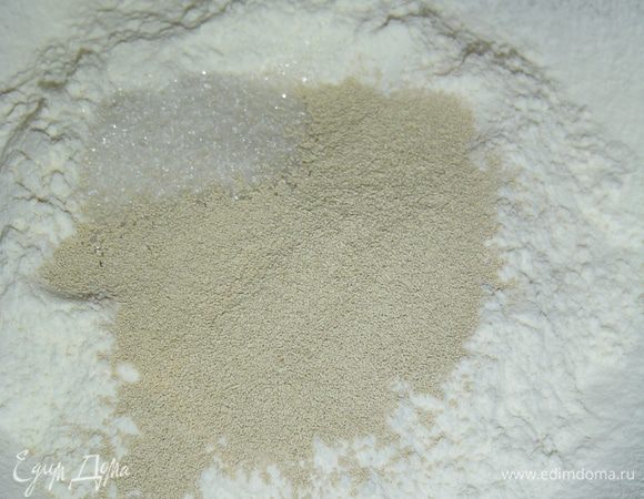 В миску насыпаем 100 г просеянной муки, к ней добавляем  ложку сахара и сухие дрожжи.