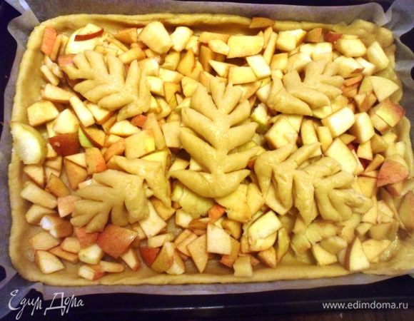 Противень застелить бумагой для выпечки от HOMEQUEEN CORPORATION, раскатать тесто, оставив немного для украшения и выложить пласт теста на противень.  Сверху выложить яблоки и украсить остатками теста, вырезав из него разные фигурки. Поставить выпекаться в разогретую до 180 градусов духовку на 30-35 минут.