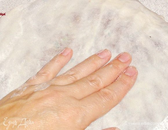 Из получившейся части руками сформуйте круглую (по возможности ) лепешку. Не страшно, если у вас будет рваться тесто, присыпьте это место мукой. Тесто будет почти прозрачным.