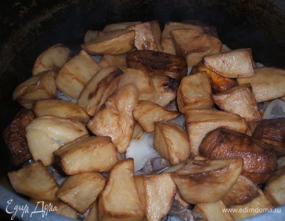 Затем нарезаем полукольцами лук, кладем поверх мяса и сверху выкладываем наш жаренный картофель. Накрываем крышкой, убавляем газ до минимума и томим так около 1 час.