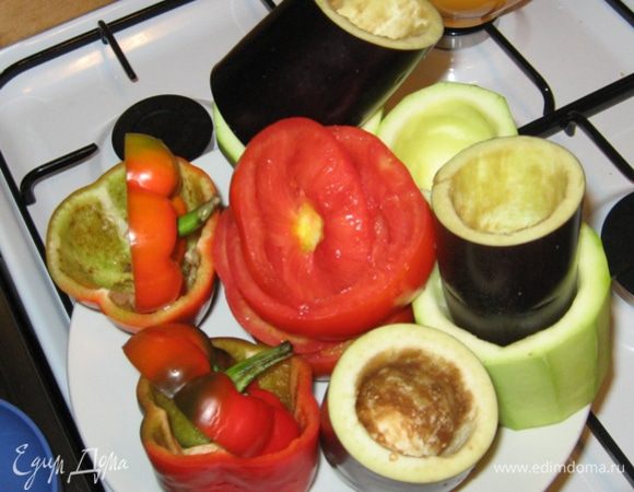 Теперь подготовим овощи для фарширования. Начнем с баклажана. Срезаем "попку" и разрезаем его поперек на высоту помидор и перцев. Аккуратно, чтобы не пробить дно, чайной ложкой удаляем сердцевину. Кабачок чистим от кожуры и подготавливаем аналогично баклажану. Теперь их надо приварить в подсоленной воде. Сначала в кипящую воду опускаем баклажан на 2 минуты, затем выкладываем к нему кабачок и буквально через минуту сливаем воду. У помидора и перца срезаем шляпки и точно также удаляем сердцевинки.