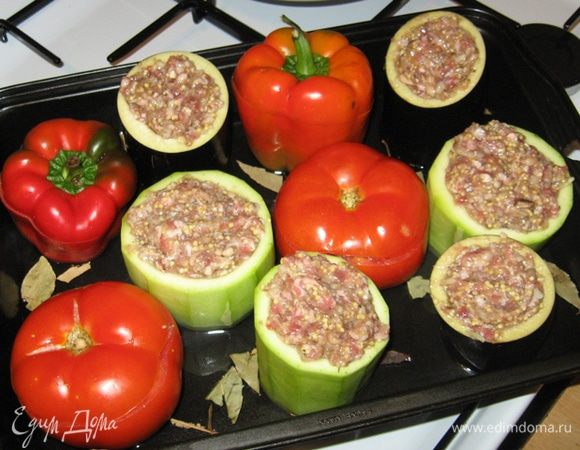 Тем временем пшенка сварилась и стекла на сите от лишней влаги. Вмешиваем ее в фарш, начиняем наши овощи, в противень, где они будут выпекаться, добавляем кипятка, выкладываем в воду лаврушку и убираем все на 40 минут в духовку при 200 градусах.