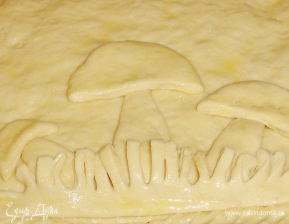 Пирог смажьте яйцом. Выложите грибочки и тоже смажьте яйцом. Дайте пирогу немного подняться.