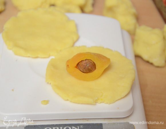 Из шарика сделать лепешку,на лепешку положить в центр фаршированную орешком(фундуком или грецким)курагу.