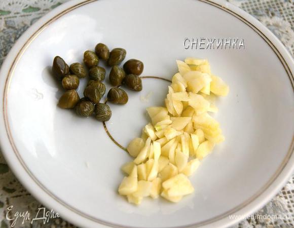 Каперсы сцеживаем и промываем. Чеснок чистим, нарезаем небольшими пластинками.