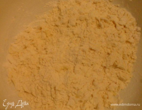 Просеять в широкую емкость муку. Сделать ямку. В центр положить размягченные кусочки масла и большую щепотку соли. Хорошенько перемешать до получения крупных хлопьев.