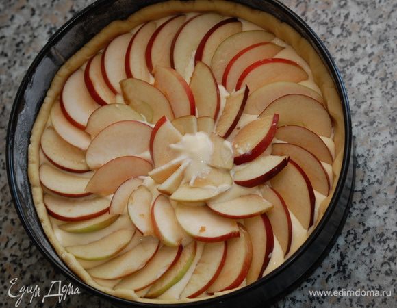 Залить тесто творожным кремом. Сверху выложить дольки яблок, слегка вдавливая их в крем.