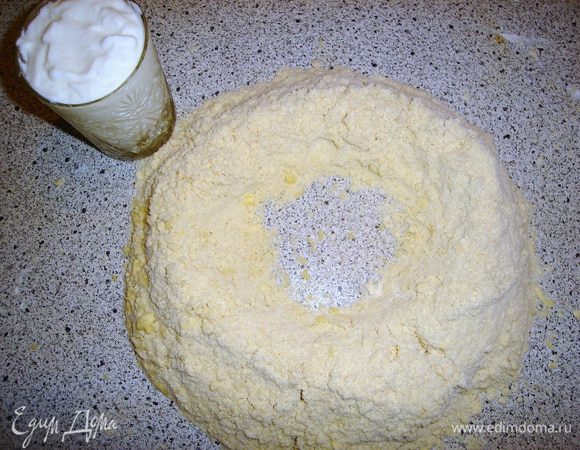 Сделать лунку. Отдельно в стакане со сметаной перемешать соду и добавить в эту лунку. Замесить тесто.