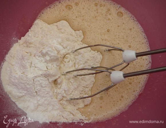 Продолжая взбивать, небольшими порциями ввести муку с разрыхлителем