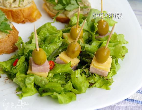 Делаем канапе из ветчины, сыра и оливок. Устанавливаем на листья салата.