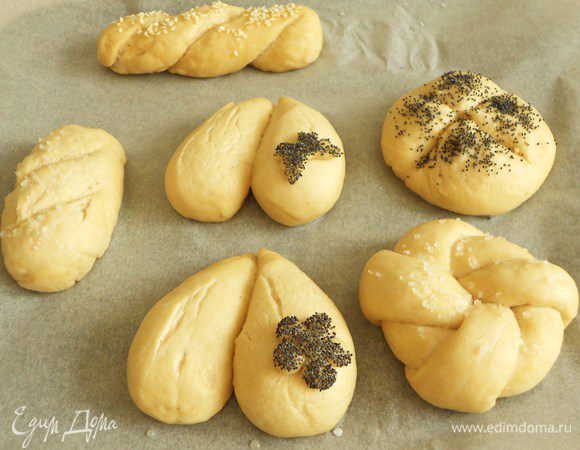 Посыпьте булочки крупной солью (желательно морской) или семенами, затем на круглых и овальных сделайте крестообразные или поперечные надрезы очень острым ножом. Мелкие фигурки обмакните в мак и приложите к булочкам.