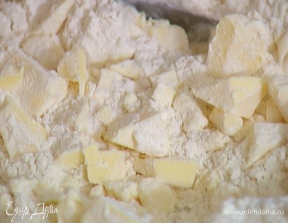 Предварительно охлажденное сливочное масло нарезать кубиками, соединить с мукой и солью и порубить в крошку.