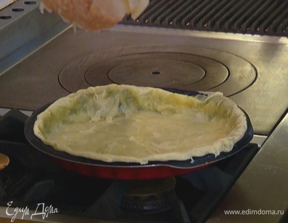 Выложить тесто вместе с бумагой в форму так, чтобы бумага оказалась сверху, сделать из теста бортики, насыпать сверху горох или крупу и отправить в разогретую духовку на 15 минут.