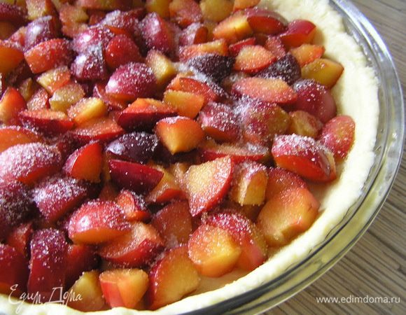 Охлажденное тесто раскатать, выложить в форму для выпечки, смазанную маслом, сверху выложить нарезанные сливы, посыпать сахаром.