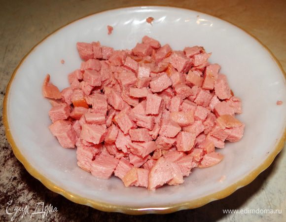 Тем временем готовим начинку.  Сосиски отварить и нарезать кубиками.