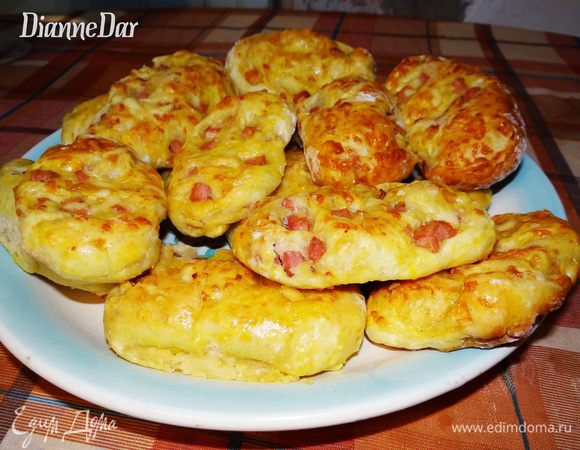 Тесто завернуть в рулет. Изделие смазать желтком+молоко. Острым ножом разрезать рулет на круглые ломтики толщиной около 2-3 см. Плюшки уложить на противень, снова смазать желтком (уже в положении "лежа"), оставить на 10 минут для расстройки. Выпекать плюшки 10-20 минут при температуре 180-200*С. 
Когда увидите, что изделия уже почти готовы (примерно до готовности осталось минутки 2), то достаньте их, пересыпьте оставшимся сыром и снова в духовку. Хочу сделать акцент на умопомрачительном запахе плюшек! Сыр внутри теста растаял  во всем доме царит божественный запах пиццы!;-) Удержатся невозможно, а с утренним чаем...Заряд энергии и хорошего настроения  на целый день! Удачи вам и приятного аппетита!