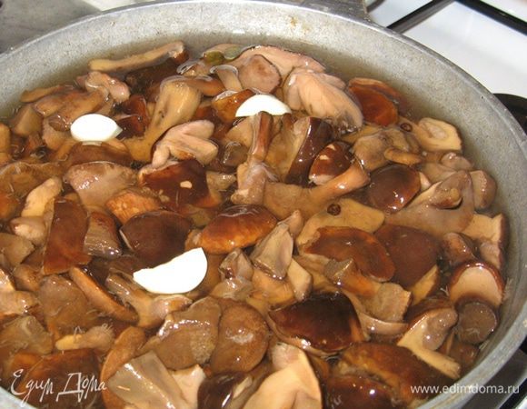 В кипящий маринад добавьте грибы, разрезанный на части чеснок, дайте закипеть, убавьте огонь и засеките 10 минут. В самом конце влейте уксус, перемешайте и сразу же разложите по банкам. Закатайте, поставьте вверх дном, накройте одеялом и дайте остыть.