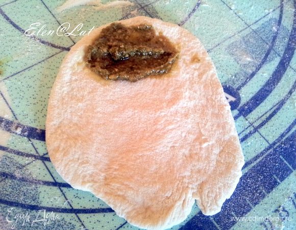 Теперь каждую булочку раскатать или размять ладошкой и положить на один край соус песто, примерно одну чайную ложку.