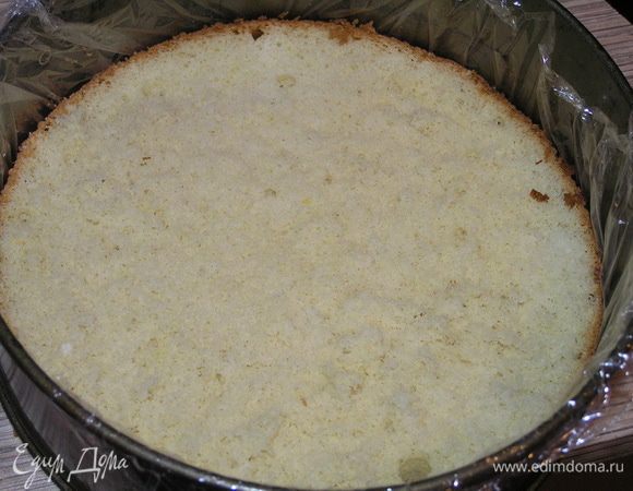 Застелить разъемную форму для торта пищевой пленкой, на дно выложить бисквитный корж. 