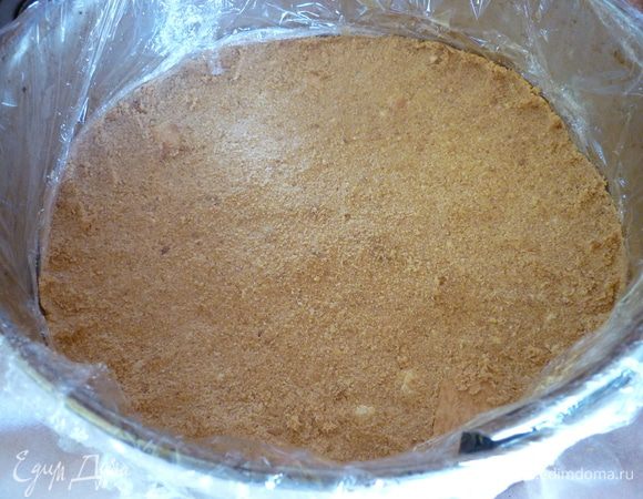 На дно формы положить пекарскую бумагу,а бока обматайте плёнкой пищевой.Растопите сливочное масло,из печенья сделайте крошку.Смешайте полученные ингредиенты,выложите полученную массу на дно формы,разровняйте и поставьте в холодильник на 1 час.