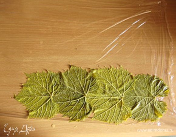Итак, все подготовлено, теперь нужно собрать рулет.Сначала разложите пленку на столе, она должна быть по длине около 50 см. И выложите ее виноградными листьями (лицевой стороной вниз) так, чтобы получился прямоугольник приблизительно 25х35 см.