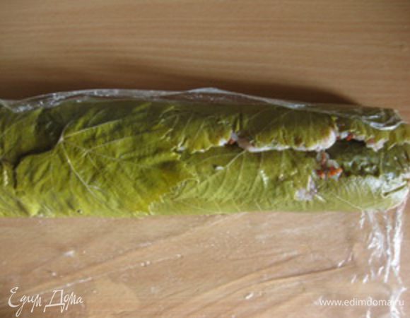Положить рулет швом вверх и "заклеить" его виноградными листьями.