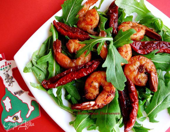 На тарелке сделать подушку из рукколы, выложить креветки (теплые, не горячие), украсить дольками вяленых помидоров.