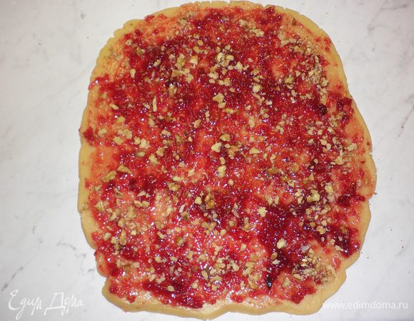 Достать тесто из холодильника.Каждый шар раскатать в прямоугольник, смазать джемом (у меня использовался брусничный) и посыпать орехами.