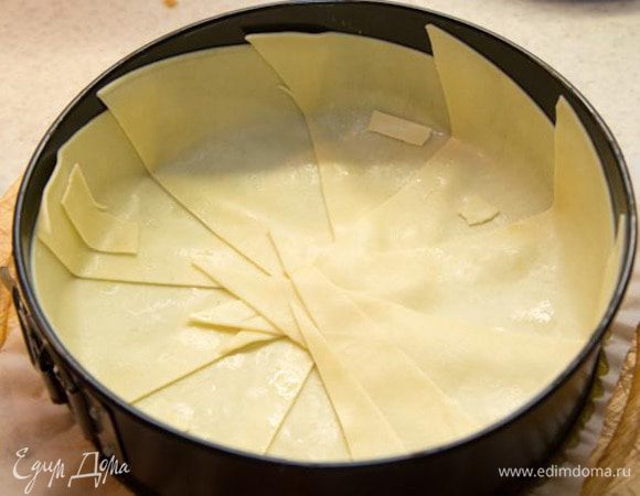 2. Теперь приступим непосредственно к приготовлению нашего блюда. Листы лазаньи отварить в хорошо подсоленной воде в течение 5 минут.  Нужно это для того, чтоб листы стали гибкие. Вынуть из воды и разложить на гладкой поверхности (стеклянная/пластмассовая досточка или тарелка),  так чтоб листы не соприкасались, иначе они слипнуться. Форму для выпечки смазываем щедро маслом. Листы лазаньи нарезаем по диагонали (у нас получаются прямоугольные  треугольники) и выкладываем на дно формы, формируя при этом бортики. Если где-то образовались трещинки, то их можно прикрыть кусочками из одного из листов, они прекрасно приклеиваются и начинка не протечет. Взбиваем в мисочке вилочкой 1 яйцо и смазываем им листы лазаньи по всей внутренней поверхности нашей «основы пирога». 