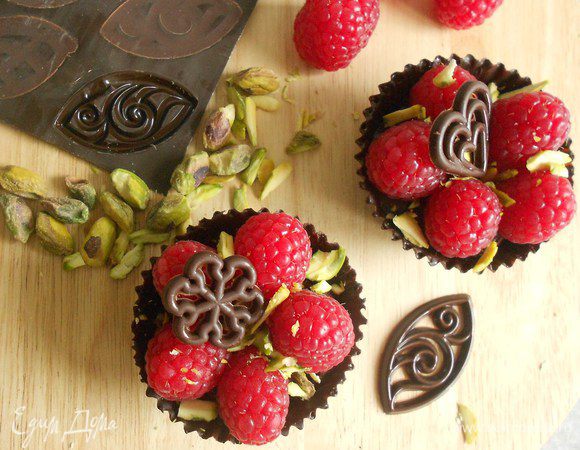 Выложить ягоды в корзинки, посыпать фисташками, при желании украсить  готовыми шоколадными фигурками.