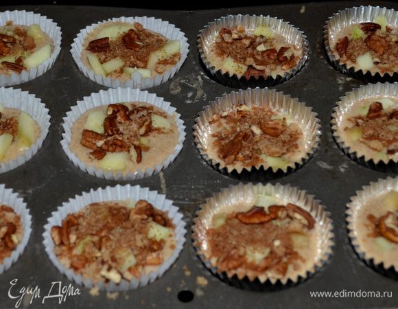 Тесто разольем по формочкам на 2/3 /при выпечке тесто поднимется/, выход примерно получается 12-16. Порезанные кусочки яблок можно смешать с тестом или разложить уже в приготовленное тесто по формочкам. Затем сверху выложить орехи с корицей и сахаром. Поставить в разогретую духовку.