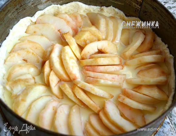 В форму с тестом наливаем часть заливки. На неё красиво и плотно укладываем дольки яблок.