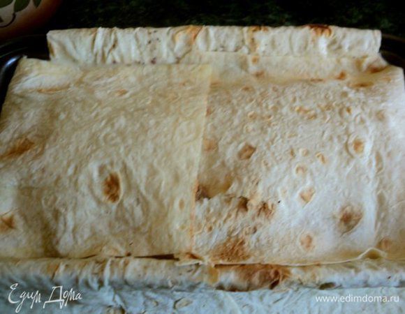 Накрыть двумя слоями лаваша и снова налить заливку и выложить начинку.Сверху накрыть свисающими краями лаваша, смазывая их заливкой. 