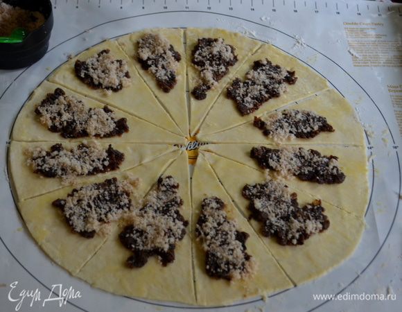 Раскатаем тесто в круг на припыленной поверхности мукой.Разрежем на 12 или 16 частей.Смажем яйцом поверхность,выложим начинку.