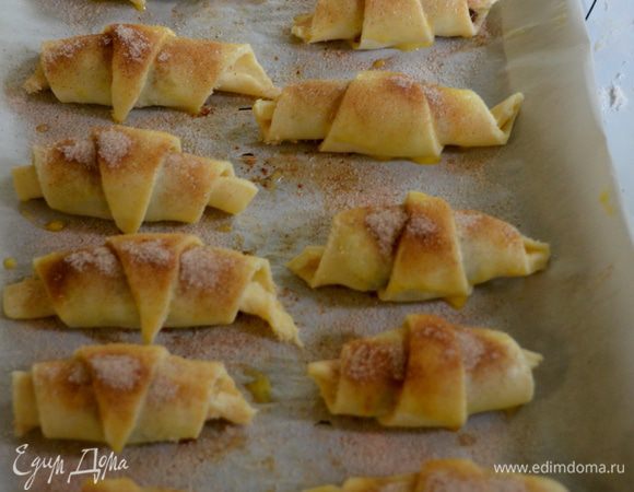 Свернем каждую часть в виде круассана.Выложим на противень с пергаментной бумагой для выпечки на расстояние друг от друга.Смажем яйцом каждый ругелаш и посыпаем сверху сахаром с корицей.