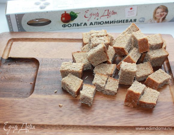 Приготовить чесночные гренки. Ржаной хлеб натереть зубчиком чеснока, порезать мелкими кубиками и поджарить на сухой сковороде. Посолить по вкусу. 