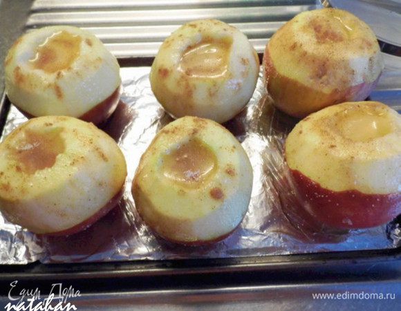 Яблоки поставьте на противень, на дно которого влейте воду. Противень разместите в духовом шкафу на решетке, расположенной на среднем уровне. Установите температуру 200°C, а таймер — на 25–30 минут. Будьте внимательны: каждый сорт яблок запекается по-разному.