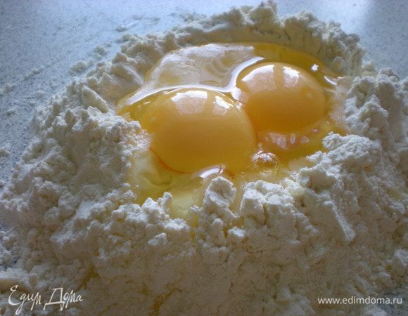 Тесто. Насыпать муку на стол, сделать кратер (ямку), разбить яйца и добавить оливковое масло.