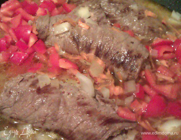 Добавляем перец к мясу, заливаем бульоном. Тушим 20 мин на слабом огне, накрыв крышкой, переворачиваем на другую сторону и тушим еще 20 мин.