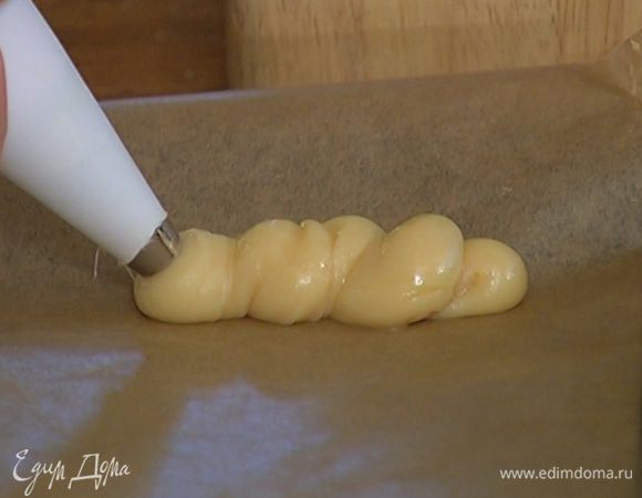 Половину теста ложкой выложить на противень в виде круглых пирожных, оставшееся тесто поместить в кондитерский мешок и выдавить из него пирожные продолговатой формы.