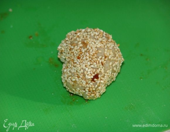 Скатать тесто в колбаску, нарезать ее кружками, размять руками каждый кружок в лепешку толщиной 0,5 см.Положить в центр каждой лепешки по 1 ст. л. начинки. Слепить края, скатать тесто в шарик. В одну миску налить  холодную воду, в другую насыпать кунжут. Смачивать каждый шарик в воде и обмакивать в кунжут. Плотно прижимать семена кунжута руками. 