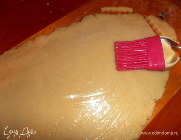 Затем раскатываем на доске тесто толщиной примерно в 0,5 см и смазываем слегка взбитым белком.