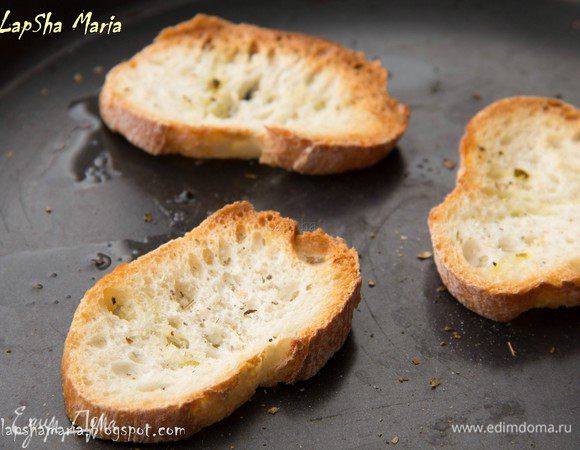 Духовку разогреваем до 220 С, выкладываем на противень или в форму ломтики багета (можно использовать вчерашний, чуть подсушенный хлеб), присыпаем французскими травами и сбрызгиваем оливковым маслом. Ставим в духовку до легкой румяности. 