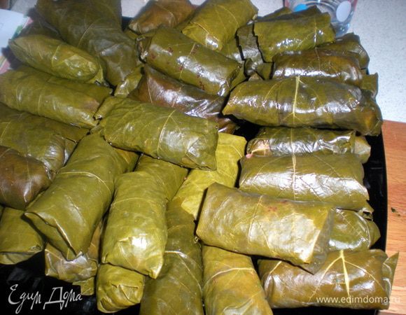 Подготовленную долму сложить плотными рядами в кастрюлю на слой листьев.Допустимо по верх нижнего слоя выложить еще один ряд.