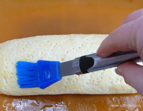 Рулет слегка приплюснуть, сделать вилкой наколы и смазать яйцом. 