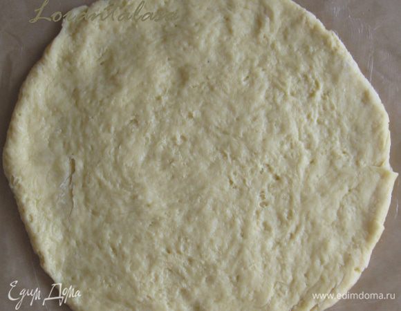 Лист пергамента смазать кусочком сливочного масла. На него выложить тесто и сформировать руками круг диаметром немного большим, чем диаметр формы - для бортиков торта.  У меня форма диаметром 24 см.
