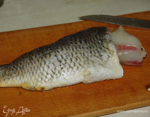 Рыбу почистить (брюшко не разрезать), плавники не вырезать, голову отделить, жабры удалить (если планируете подавать рыбу целиком). По кругу сделать надрезы, отделяя шкуру от мяса, оставляя немного мяса на шкуре. Снятую мякоть разберите, удаляя кости. Чтобы мясо легче отделялось от костей, кости можно обдать кипятком. Мясо мелко порубить ножом. 