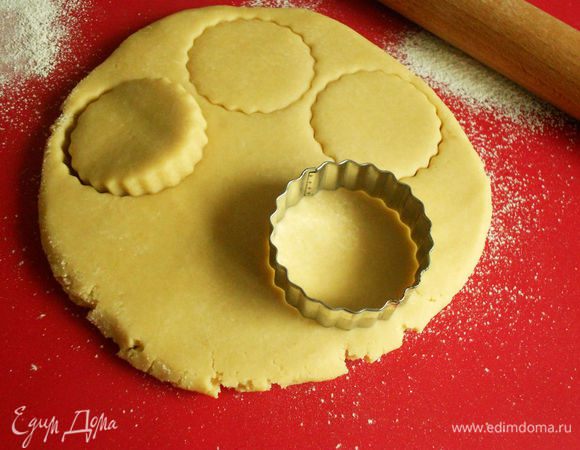 Переложите тесто не присыпанную мукой поверхность, долго не месите, а лишь слегка обомните и сформируйте шар. Раскатайте его в толстый круг диаметром примерно 18 см. Круглой формочкой диаметром 6, 5 см (обмакивая сначала в муку) или тонким стаканом вырежьте кружки из теста и поместите их на противень.