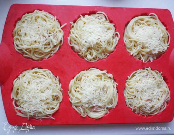 Форму для кексов (тарталеток) смазать растительным маслом. 
Спагетти с соусом выложить в формочки. Сверху посыпать оставшимся сыром. Запекать в разогретой до 180 г духовке в течение 20 мин (т к я использовала силиконовую форму и ставила ее в холодную духовку, то потребовалось еще дополнительно 10мин).